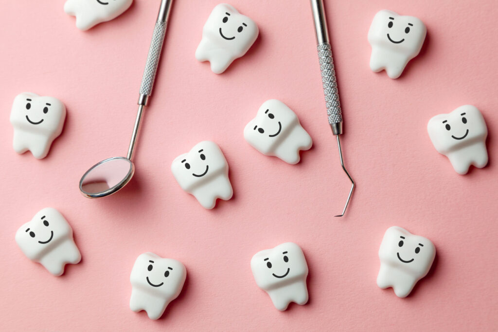 ピンク背景に散らばる歯の模型と歯科用器具