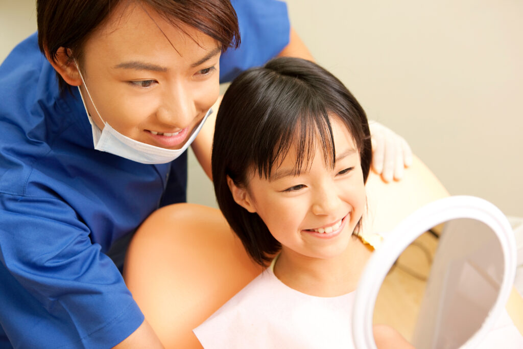 小児矯正治療に伴い歯の確認をする歯科医師もと子供